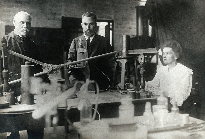 Pierre ve Marie Curie bu fotoğrafta radyoaktiviteyi ölçmekte kullandıkları kuvars basınç elektriği terazisi ve elektrometrenin başında görüntülenmiştir