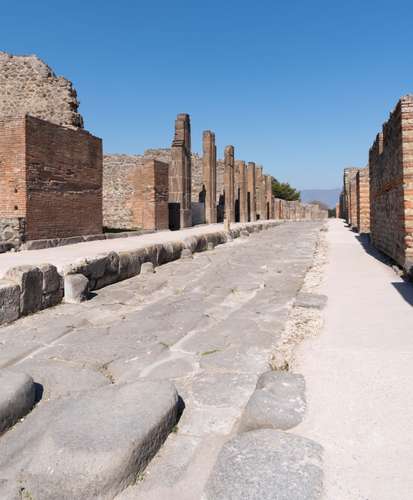Antik Pompeii'nin ana caddesi Via dell'Abbondanza. Kaldırım taşlarındaki oluklar, sokağın Roma vagonları ve arabalarının uğrak yeri olduğunu gösteriyor.