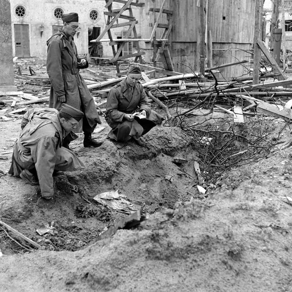 LIFE muhabiri Percy Knauth, Hitler ve Eva Braun'un intiharlarından sonra yakıldığı Reich Şansölyeliği bahçesindeki sığ siperdeki enkazı inceliyor
