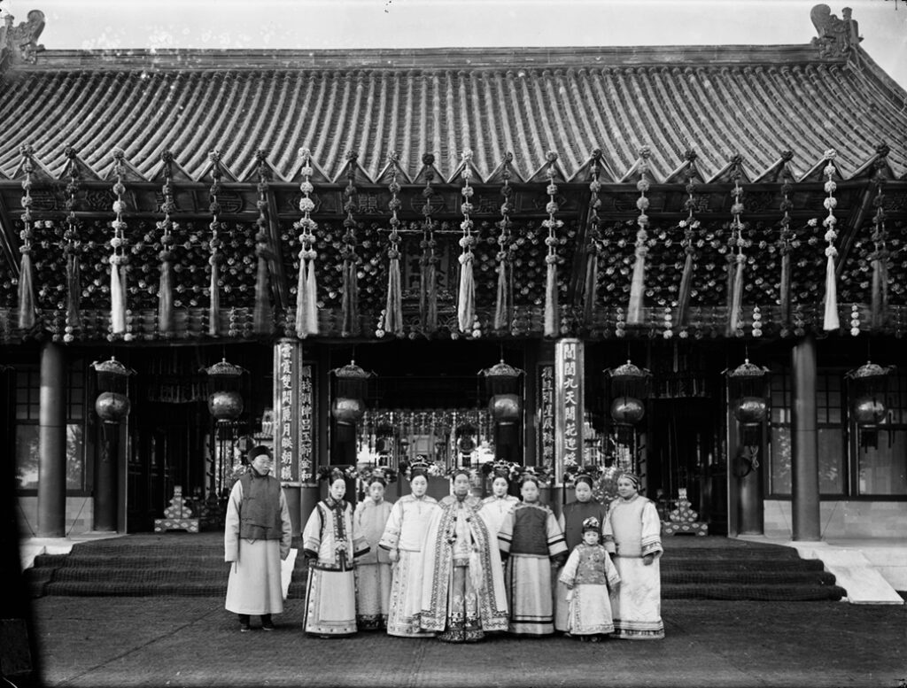 İmparatoriçe Dowager Cixi (önde ortada) saray görevlileri ve aynı zamanda yeğeni olan Guangxu İmparatoru'nun imparatoriçesi (soldan ikinci) ile beraber, 1903 civarı. Kaynak: Wikipedia