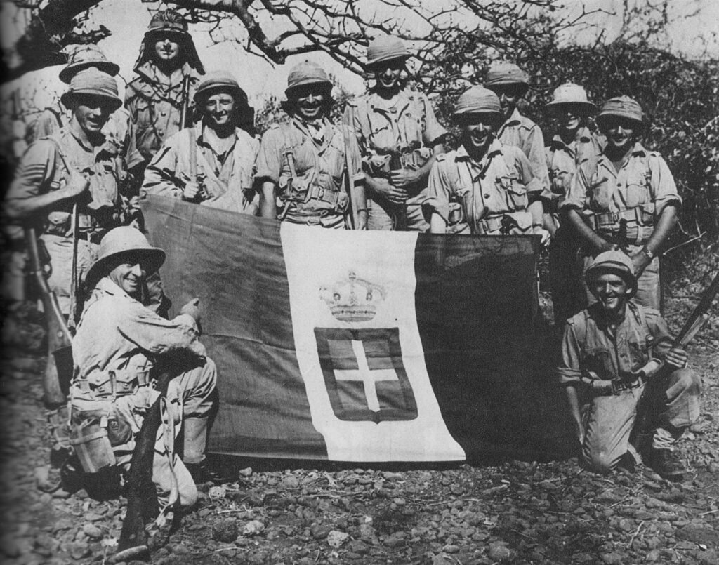 İtalyanların geri çekilmesinden sonra Moyale'de ele geçirilen bir İtalyan bayrağıyla poz veren Güney Afrikalılar. 1941
