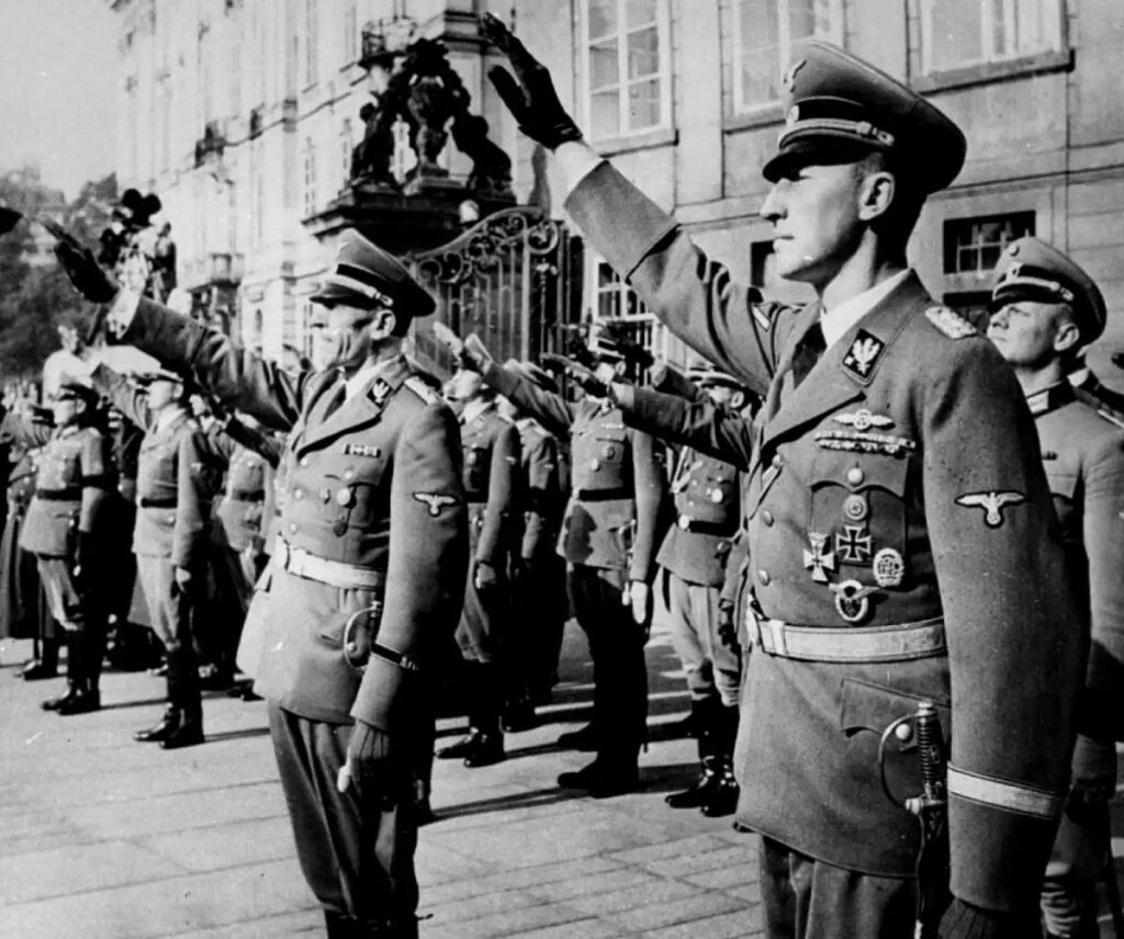 Reinhard Heydrich (sağda) ve yardımcısı Karl Hermann Frank (ortada), Heydrich'in Bohemya ve Moravya Protektorası valisi olarak göreve başlaması sırasında hazır olda bekliyorlar. Prag, Eylül 1941.
