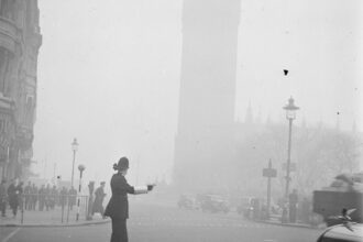 Een agent regelt het verkeer in de mist Op de achtergrond is Big Ben te zien Bestanddeelnr 254 1948