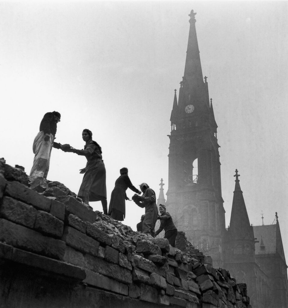 Dresden'de kadınlar yıkık bir binanın üstünden tuğlaları taşıyor.